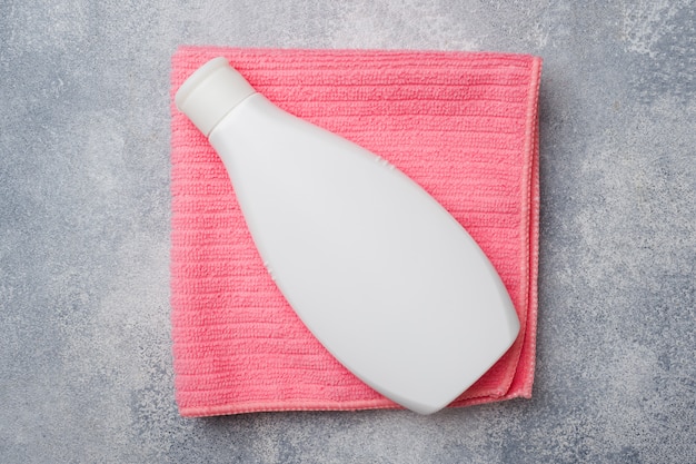 Witte plastic fles op een roze handdoek, badkameraccessoires,