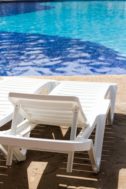 Witte plastic poolstoelen bij het zwembad.