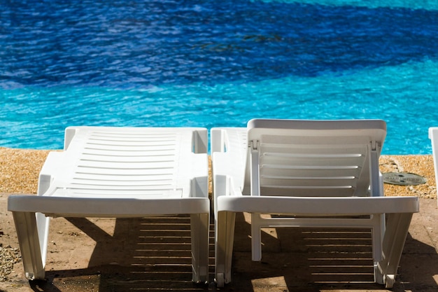 Witte plastic poolstoelen bij het zwembad.