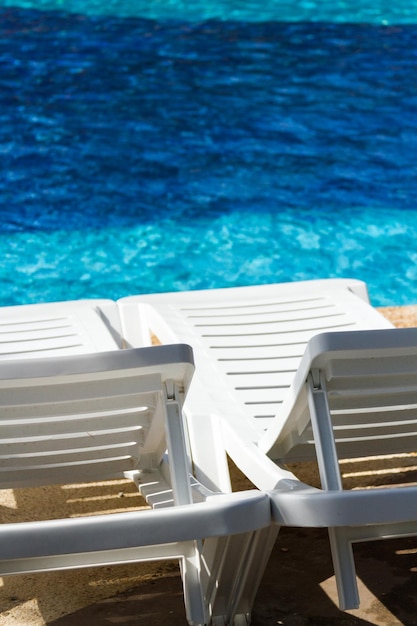 Witte plastic poolstoelen bij het zwembad.