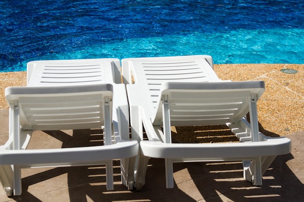 Witte plastic poolstoelen bij het zwembad.