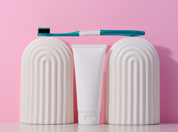 Witte plastic tube tandpasta en tandenborstel op een roze achtergrond