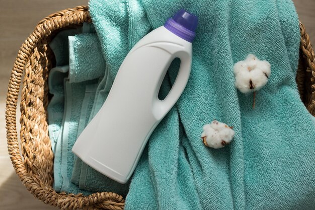 Witte plastic verpakking met wasmiddel vloeibaar waspoeder conditioner bleekmiddel vlekverwijder voor kleding terry handdoeken en katoen bloemen in een mand