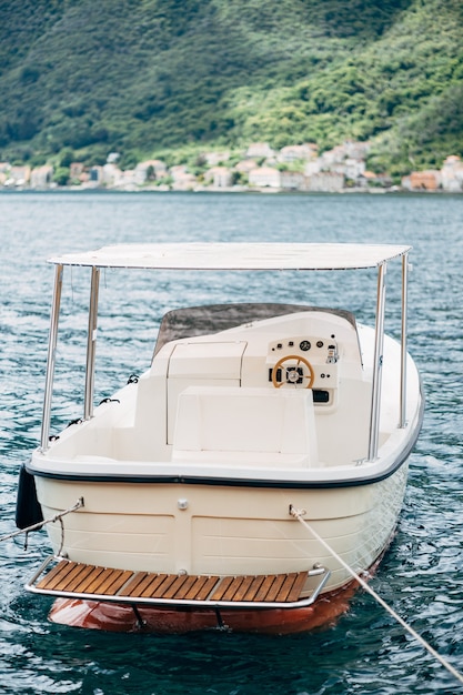 Witte plezierboot met luifel, achteraanzicht. Afgemeerd in het water.