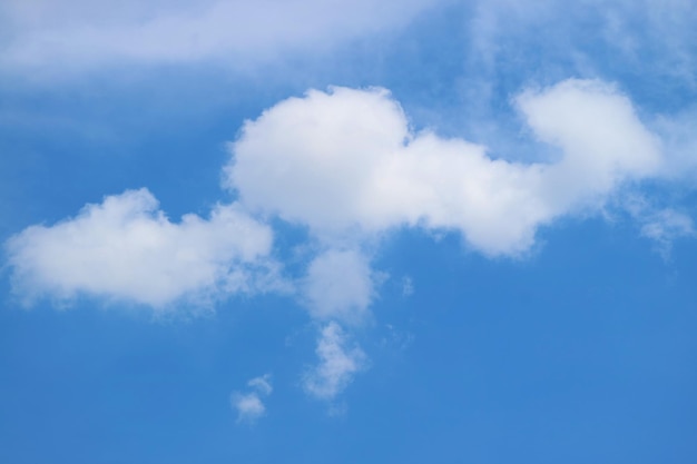 Witte pluizige wolken drijvend op heldere blauwe hemel