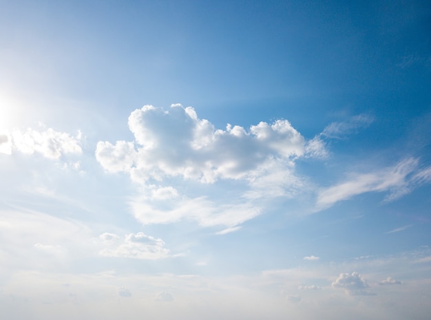 Witte pluizige wolken en felle zon op een blauwe lucht. Concept van zomer achtergrond