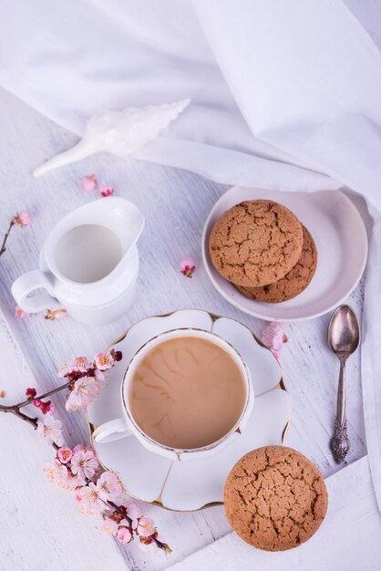 Witte porseleinen kop koffie of cacaomelkkan en versgebakken haverkoekjes Engels ontbijtstilleven met drankje en lekkers en tafelkleed