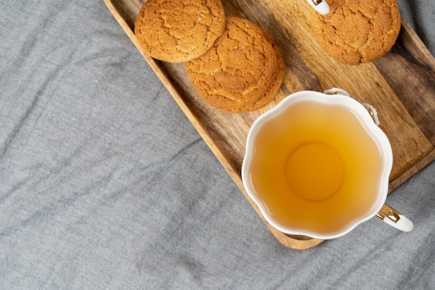 Witte porseleinkop thee en haverkoekjes op een lijst