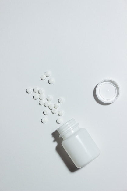 Witte pot met tabletten op een wit oppervlak. Gezondheid. Geneesmiddel.