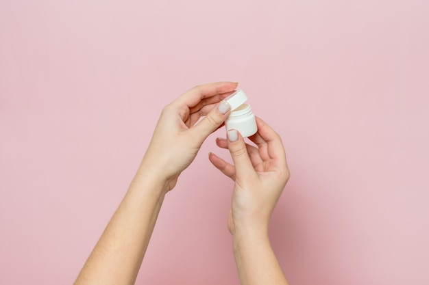 Witte pot of fles met crème zalf in de handen van de vrouw Gezichtsverzorgingsfles met cosmetisch product
