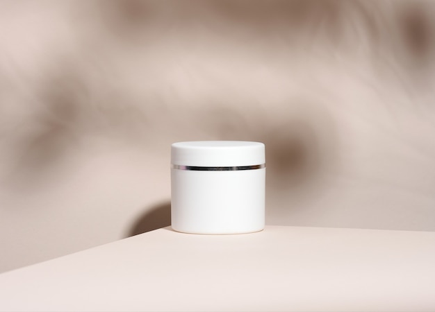 Witte pot voor cosmetica op een beige tafel. Verpakking voor crème, gel, serum, reclame en productpromotie, mock-up