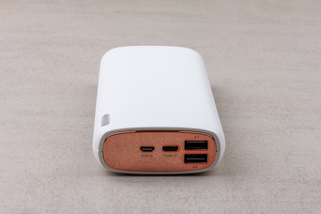 Witte powerbank voor het opladen van smartphones en verschillende digitale apparaten op een grijze achtergrond close-up