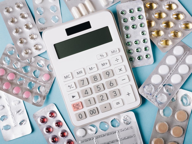 Witte rekenmachine en pillen op een blauwe achtergrond als symbool van betaalde dure medicijnen