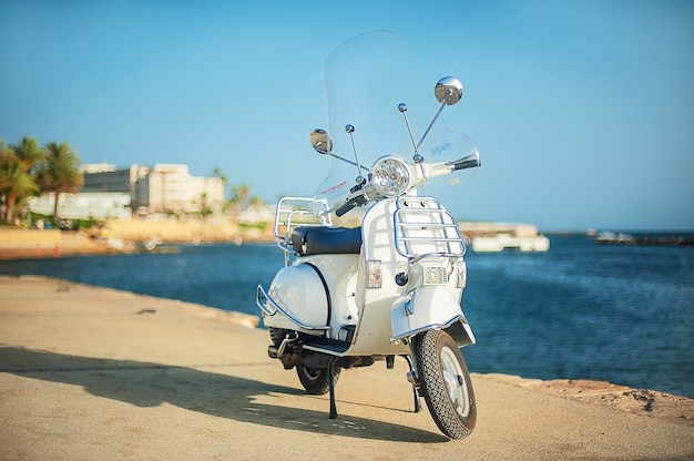 Witte retro scooter op het strand. Toeristische dijk