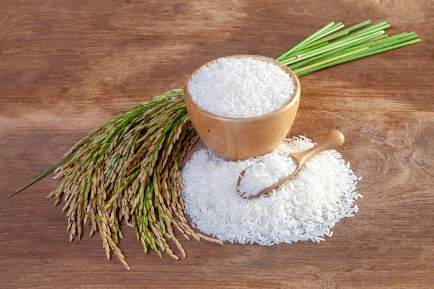 Foto witte rijst twitte rijst thaise jasmijnrijst in een houten kom en oren van rijst op houten vloerhai jasmijnrijst in een houten kom en aparte rijstaren op houten vloer