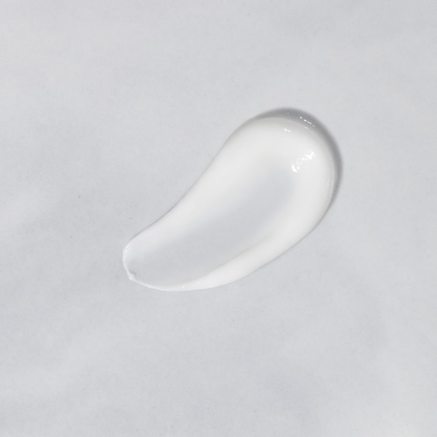 Witte schoonheidscrème uitstrijkje vlek op witte achtergrond Gezichtscrème bodylotion swipe staal