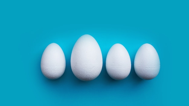 Witte schuim eieren op blauwe achtergrond. Plat lag, bovenaanzicht. Pasen-concept.