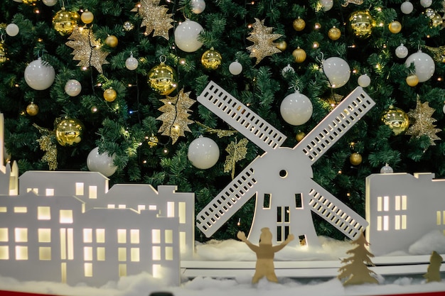 Witte silhouetten van windmolen en huizen, tegen de achtergrond van een versierde kerstboom