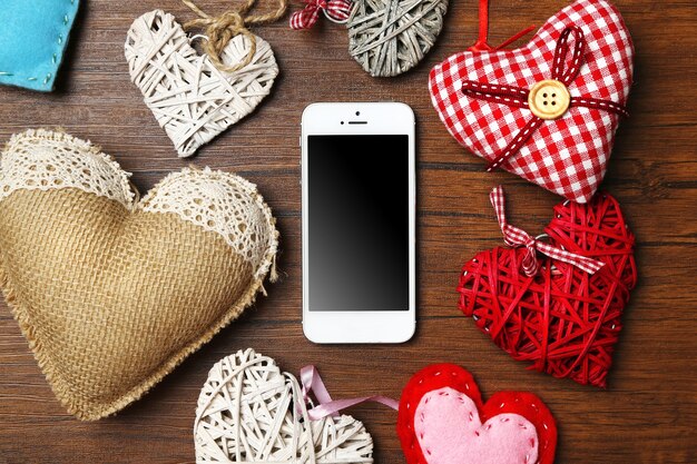 Witte slimme telefoon met hartjes op houten bureau.