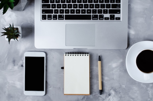 Witte smartphone met zwart leeg scherm op bureau met laptop en kopje koffie. Bespotten van telefoon.