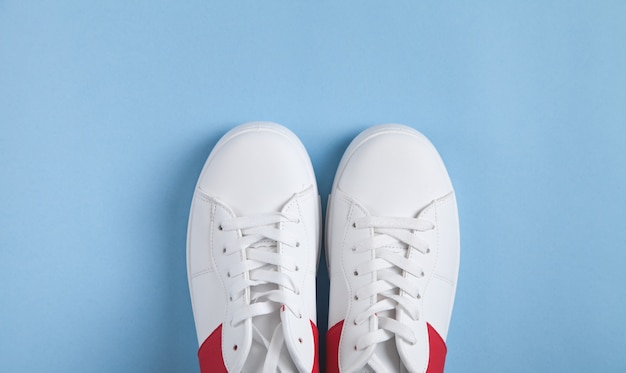 Witte sneakers op blauwe achtergrond.