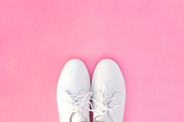 Witte sneakers op een roze achtergrond. uitzicht van boven. copyspace.