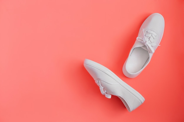 Witte sneakers op een trendy koraal achtergrond kopie ruimte