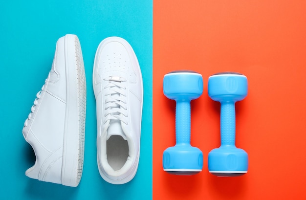 Foto witte sneakers, plastic halters op een tweekleurige tafel. sport concept. bovenaanzicht
