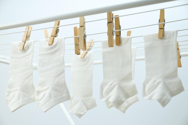 Witte sokken hangen aan droogrek op lichte achtergrond