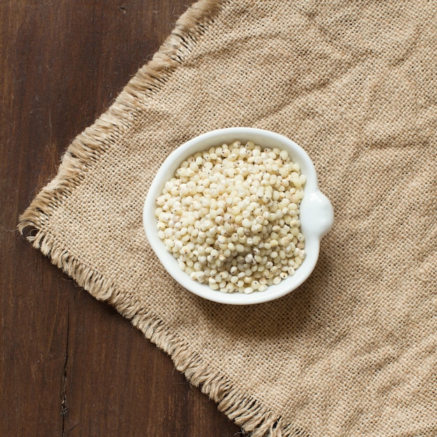 Witte Sorghum-korrel in een kom op jute