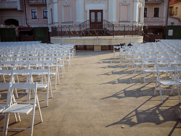 Witte stoelen voor kijkers in openluchtconcertzaal
