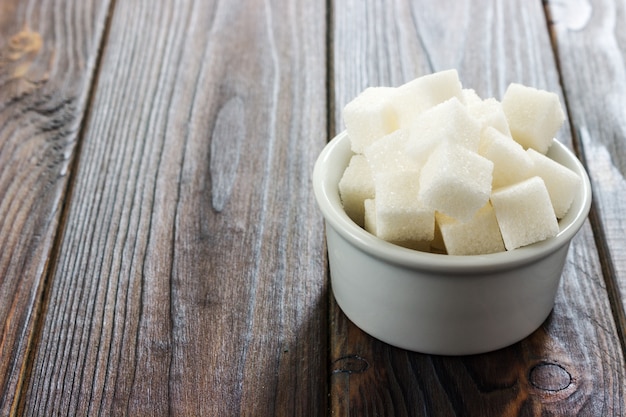 Witte suiker in kom op houten achtergrond. Selectieve focus, horizontaal. Inname van slechte calorieën