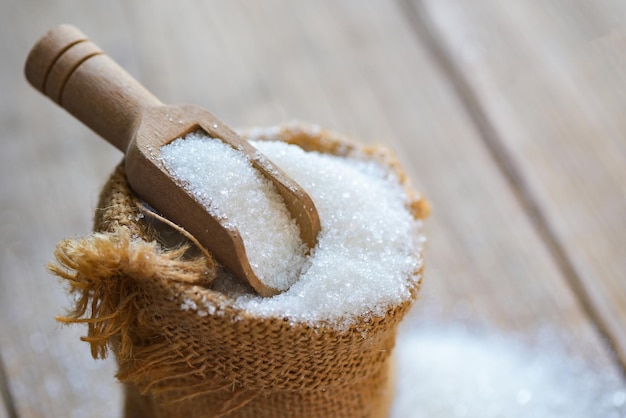 Witte suiker voor eten en snoep dessert snoep hoop zoete suiker kristallijne kristalsuiker op zak en houten achtergrond