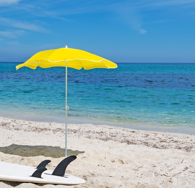 Witte surfplank en gele parasol op het zand