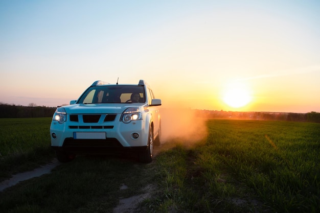 Witte suv-auto op veldweg bij zonsondergang