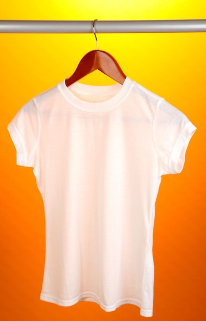 Witte t-shirt op hanger op oranje achtergrond