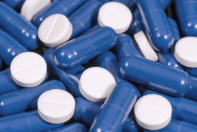 Witte tabletten en blauwe capsules close-up