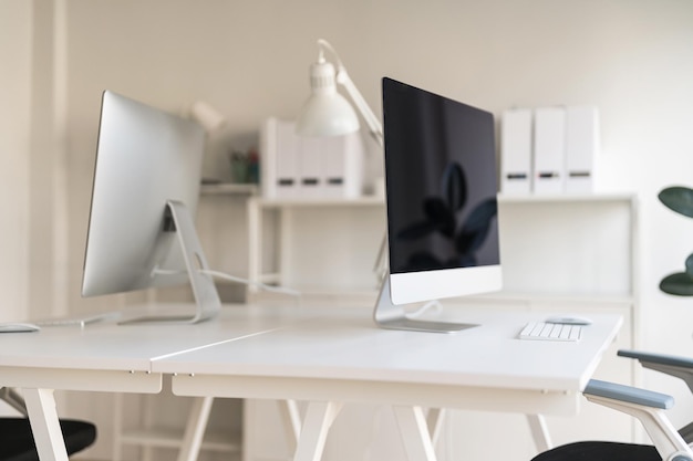 Witte tafel en stoel met computermonitor en moderne archiefkast in wit kantoor aan huis