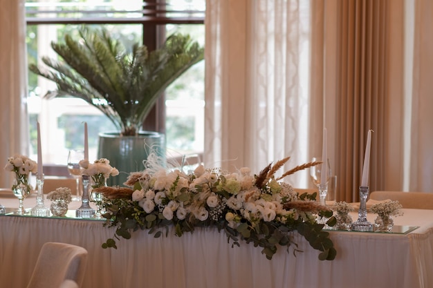 Witte tafelkleden met heldere vazen en witte chrysanten en varenarrangementen