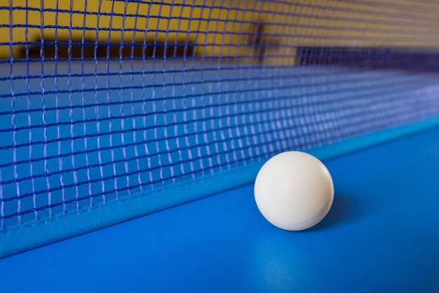 Witte tafeltennisbal op blauwe tafel met net Tafeltennis