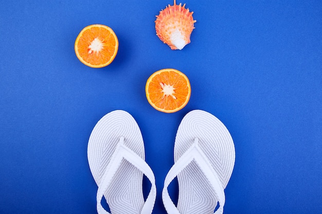 Witte teenslippers, oranje fruit, zeeschelp