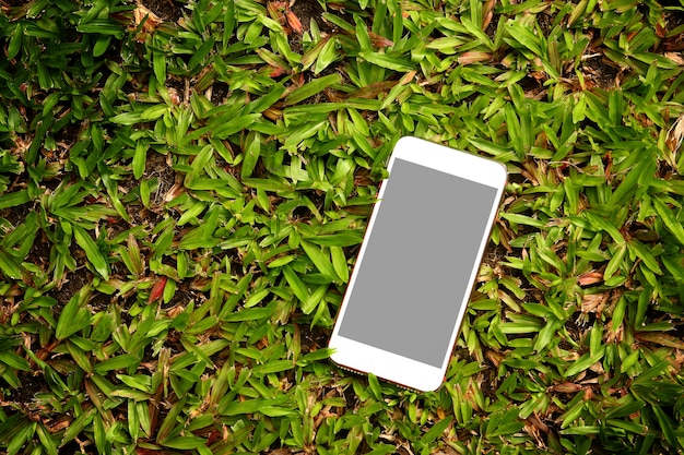 Witte telefoon Geplaatst op groen gras.