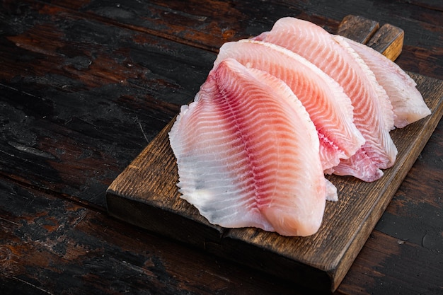 Witte tilapia visfilet bezuinigingen op donkere houten tafel