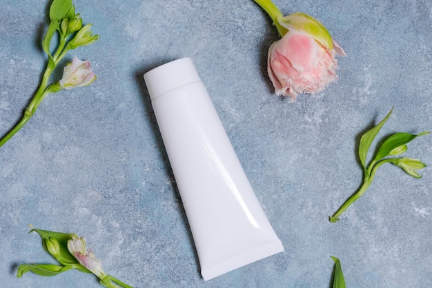 Witte tube voor crème Branding concept en rozen Tulpen op een blauwe achtergrond