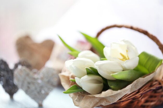 Witte tulpen in een rieten mand op een lichtblauwe tafel