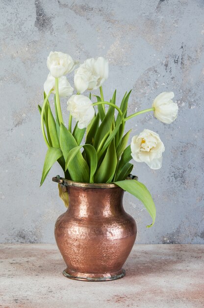 Witte tulpen in oude koperen vaas