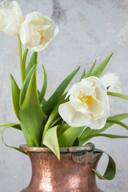Witte tulpen in oude koperen vaas