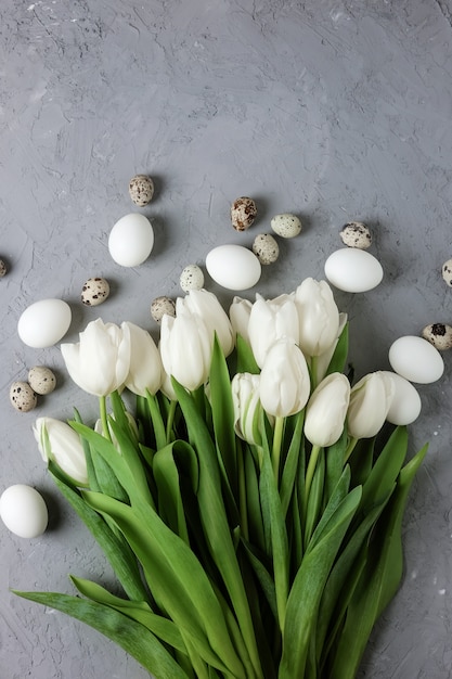 Foto witte tulpen met eieren op grijze betonnen achtergrond