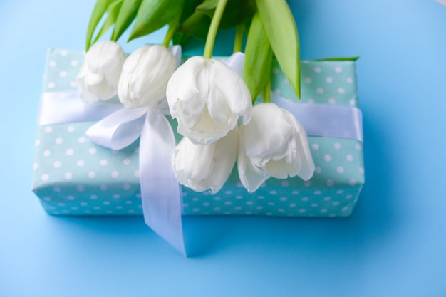 witte tulpenbloemen en giftdoos op blauw oppervlak