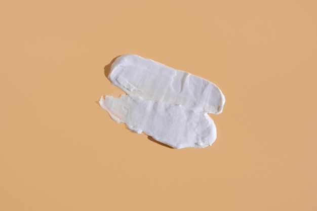 Witte uitstrijkje van cosmetische crème op een beige achtergrond Romige foundation textuur geïsoleerd